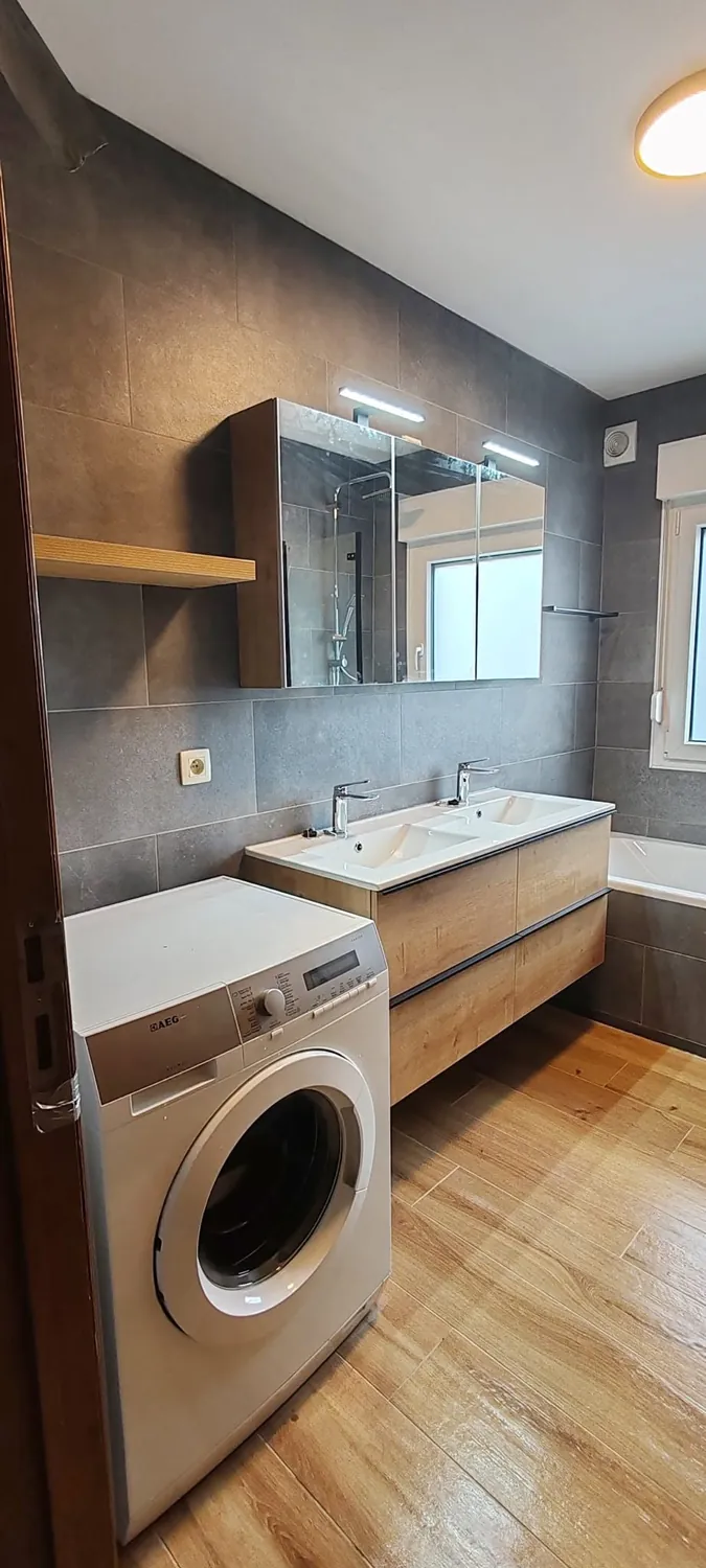 Salle de bains terminée avec meuble vasque, miroir et lave-linge intégré