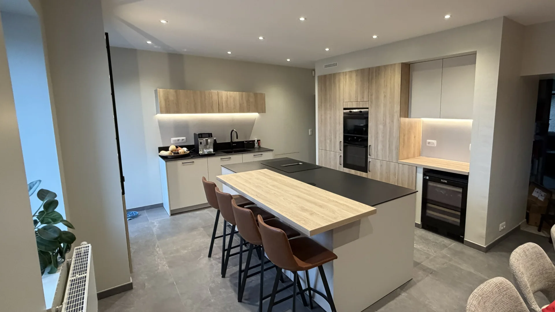 Cuisine contemporaine avec îlot central, meubles en bois clair et éclairages encastrés